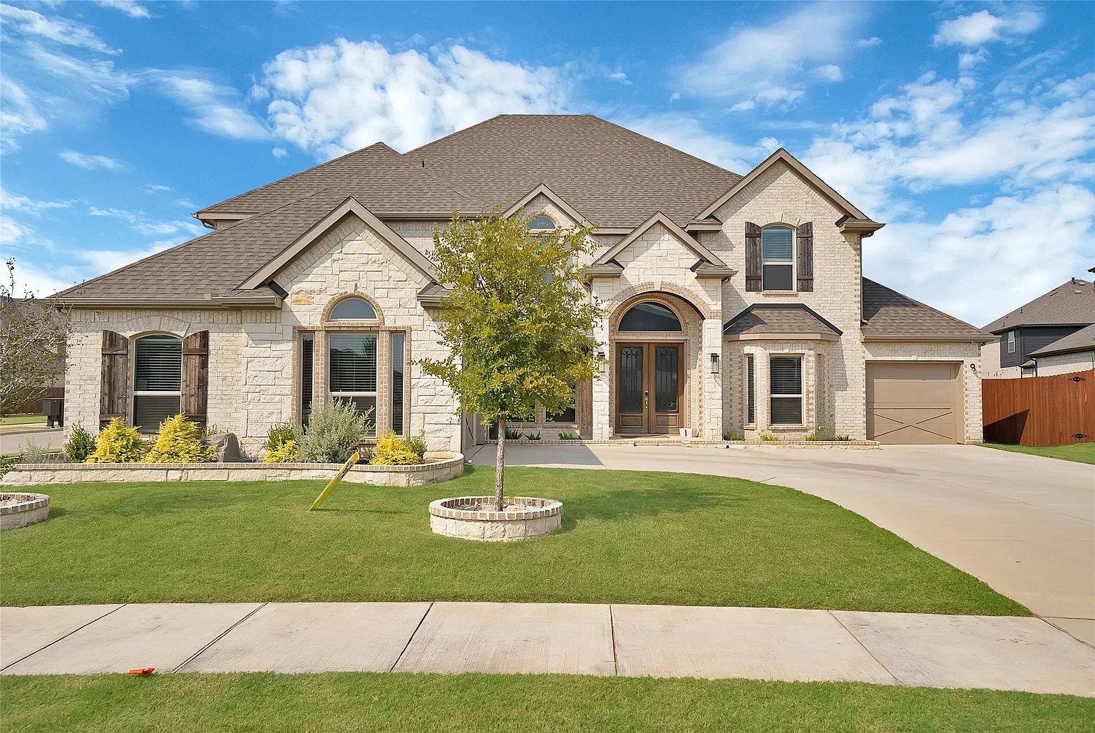 Stone and brick front exterior, lawn, tree and driveway.